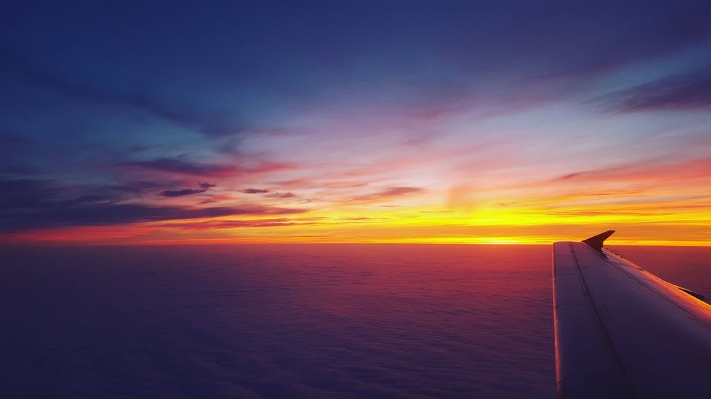 A breathtaking view of an airplane wing against a vibrant sunset sky, perfect for travel and aviation themes.