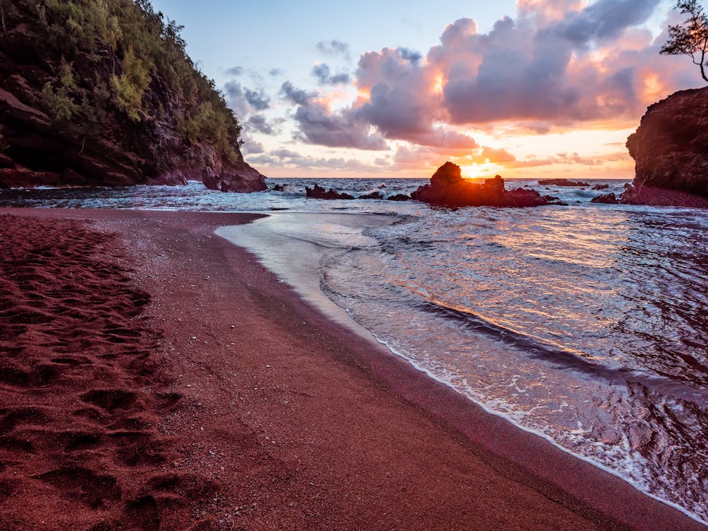 Discover the stunning sunrise over Kaihalulu Beach's unique red sands in Hana, Hawaii.